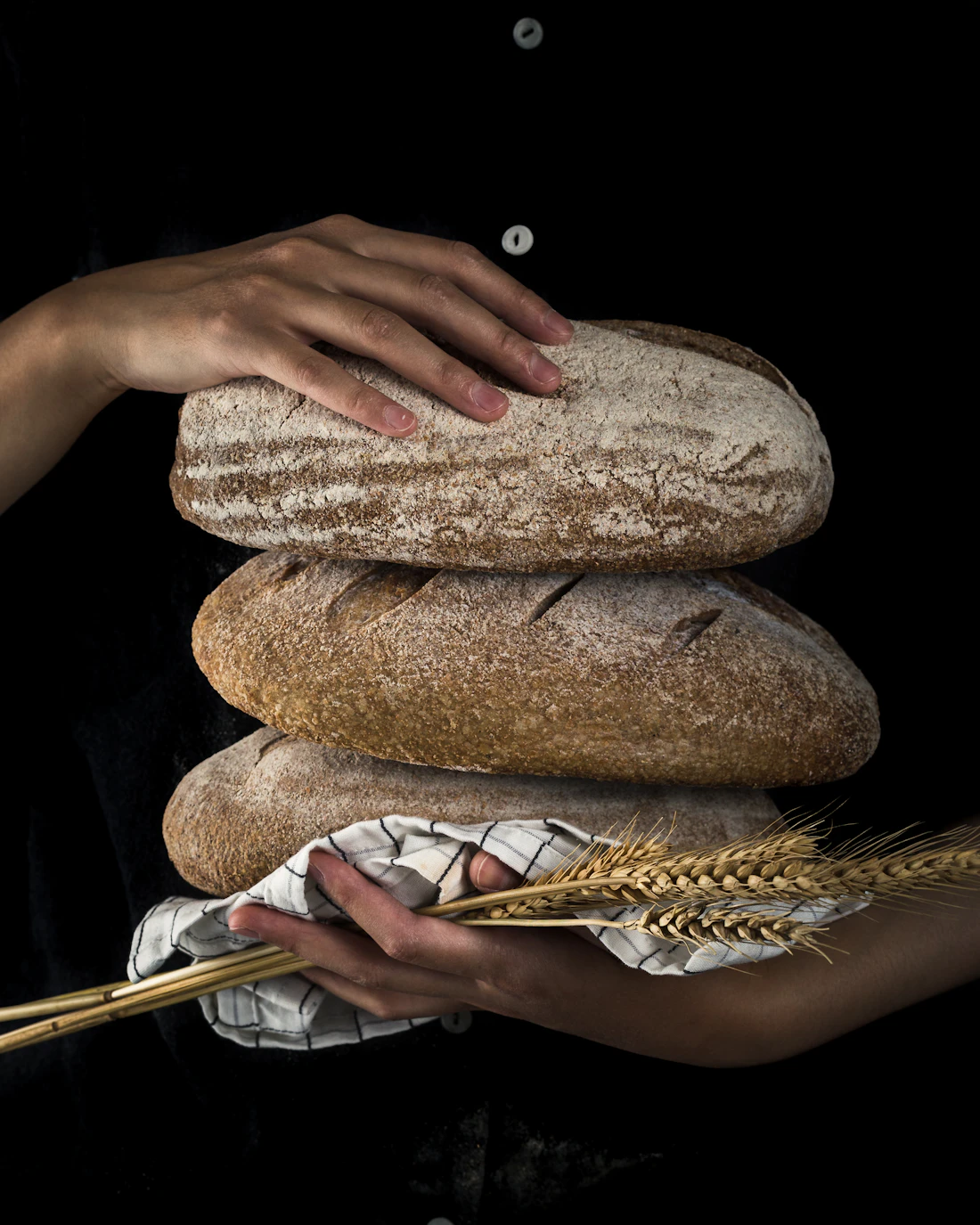 Des miches de pain au levain tenues dans les mains du boulanger