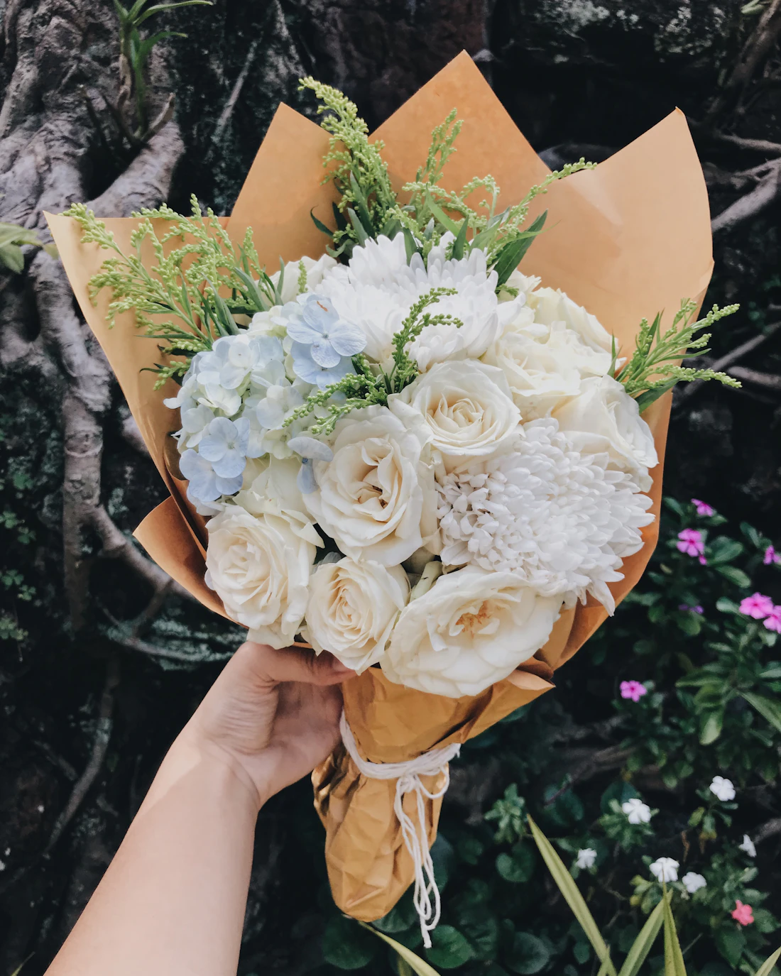 Bouquet de fleurs blanches et beiges tenu dans les bras
